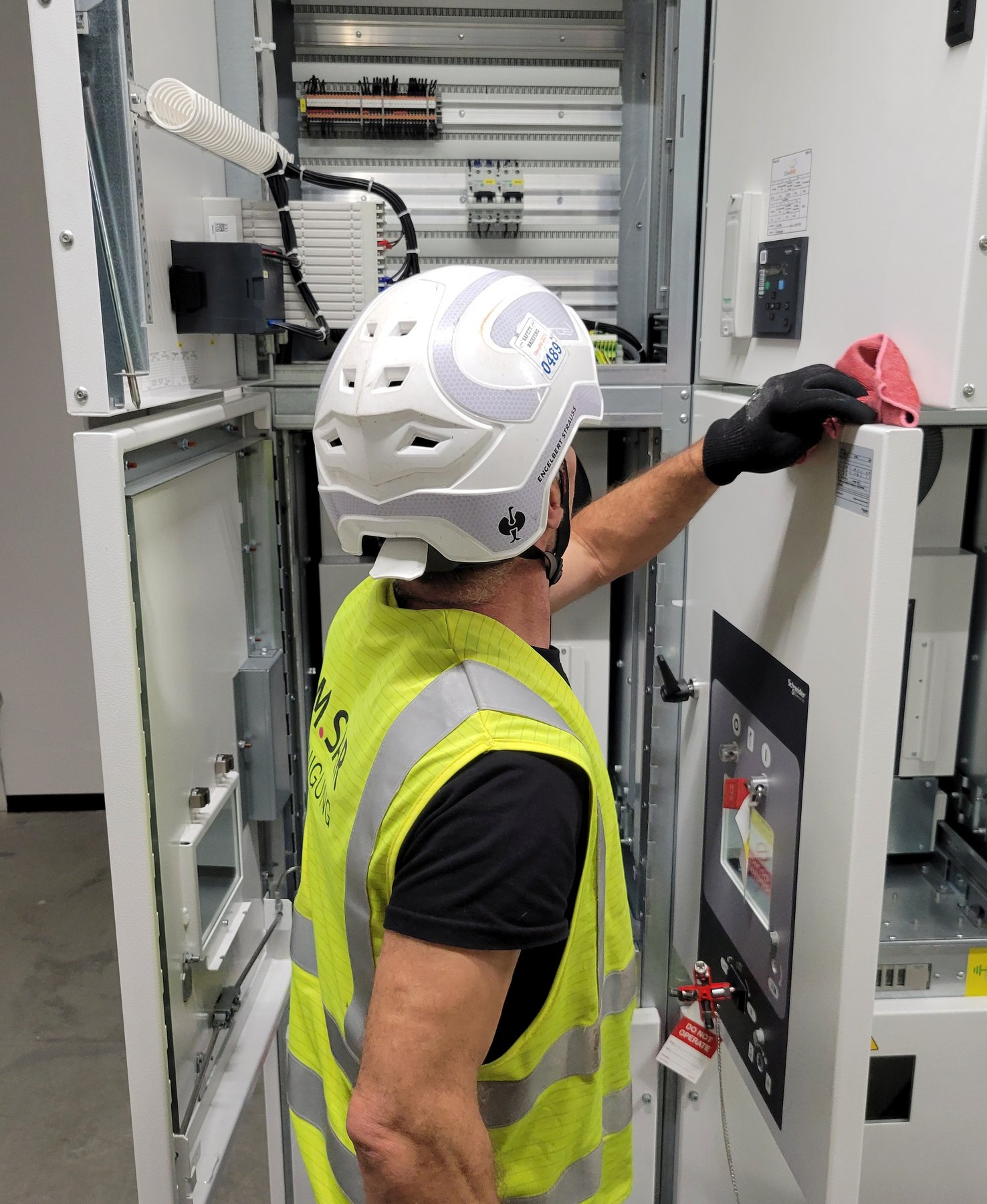 Mitarbeiter von COM.SAR IT Cleaning reinigt eine Schaltschrankoberfläche mit einem Tuch.