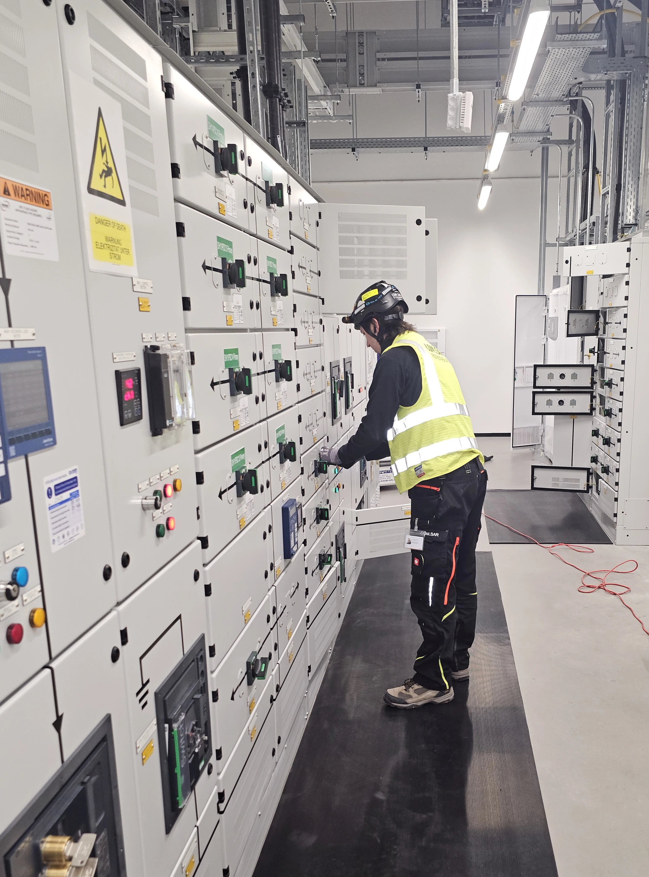 Mitarbeiter von COM.SAR IT Cleaning bei der Reinigung an einer Schaltanlagenreihe.