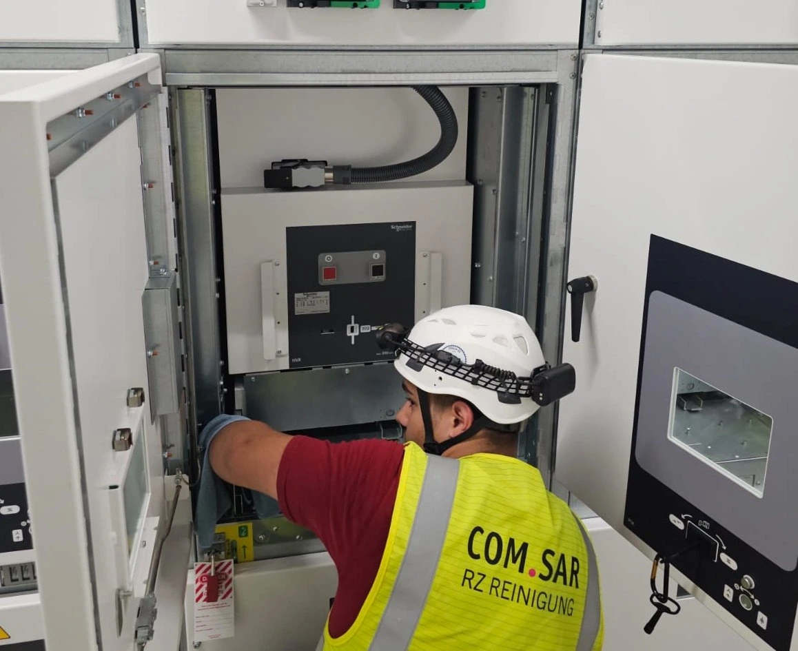 Mitarbeiter von COM.SAR IT Cleaning reinigt eine Fläche im Schaltgerätebereich.