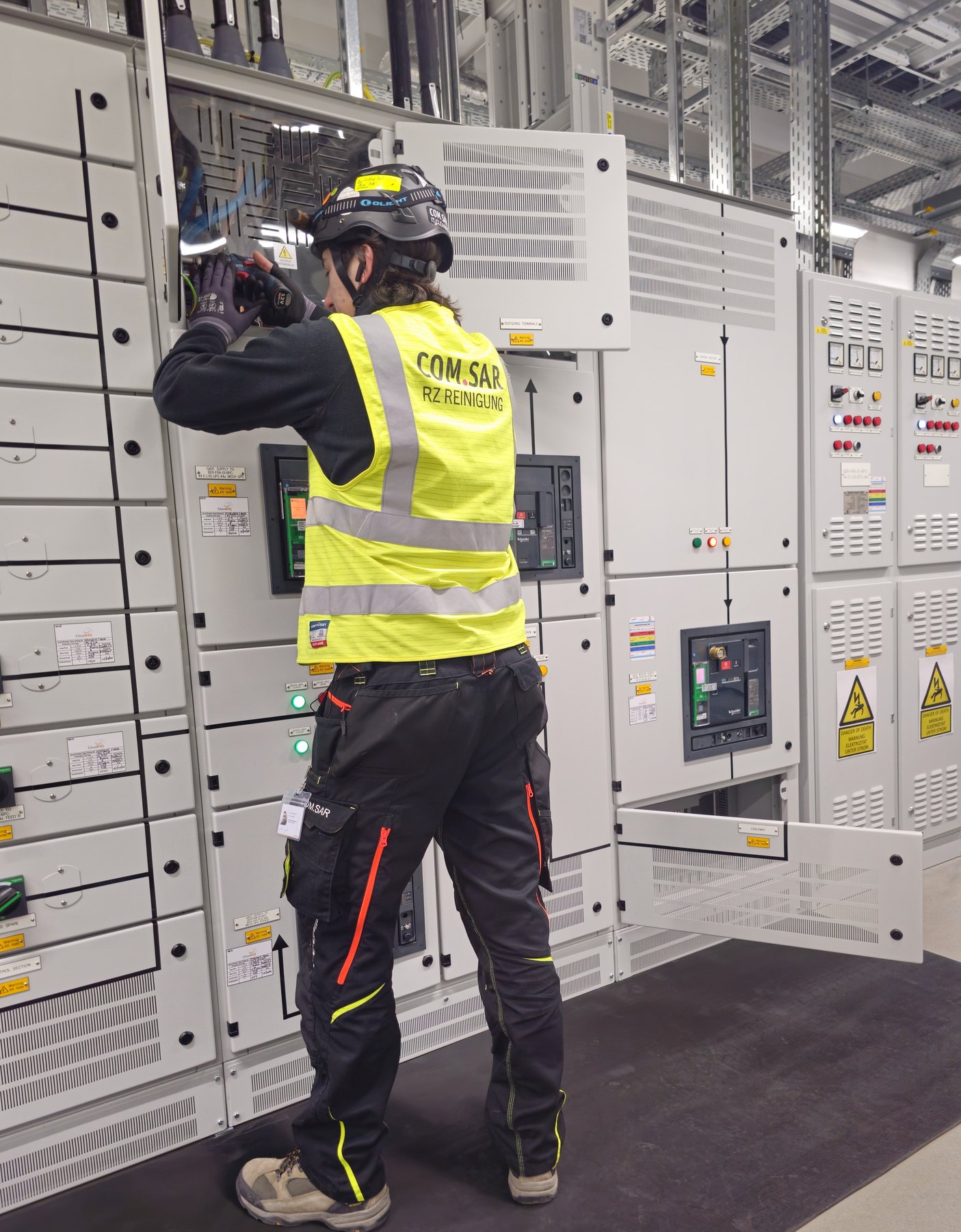 Mitarbeiter von COM.SAR IT Cleaning bei Arbeiten an einer Schaltanlagenabdeckung.