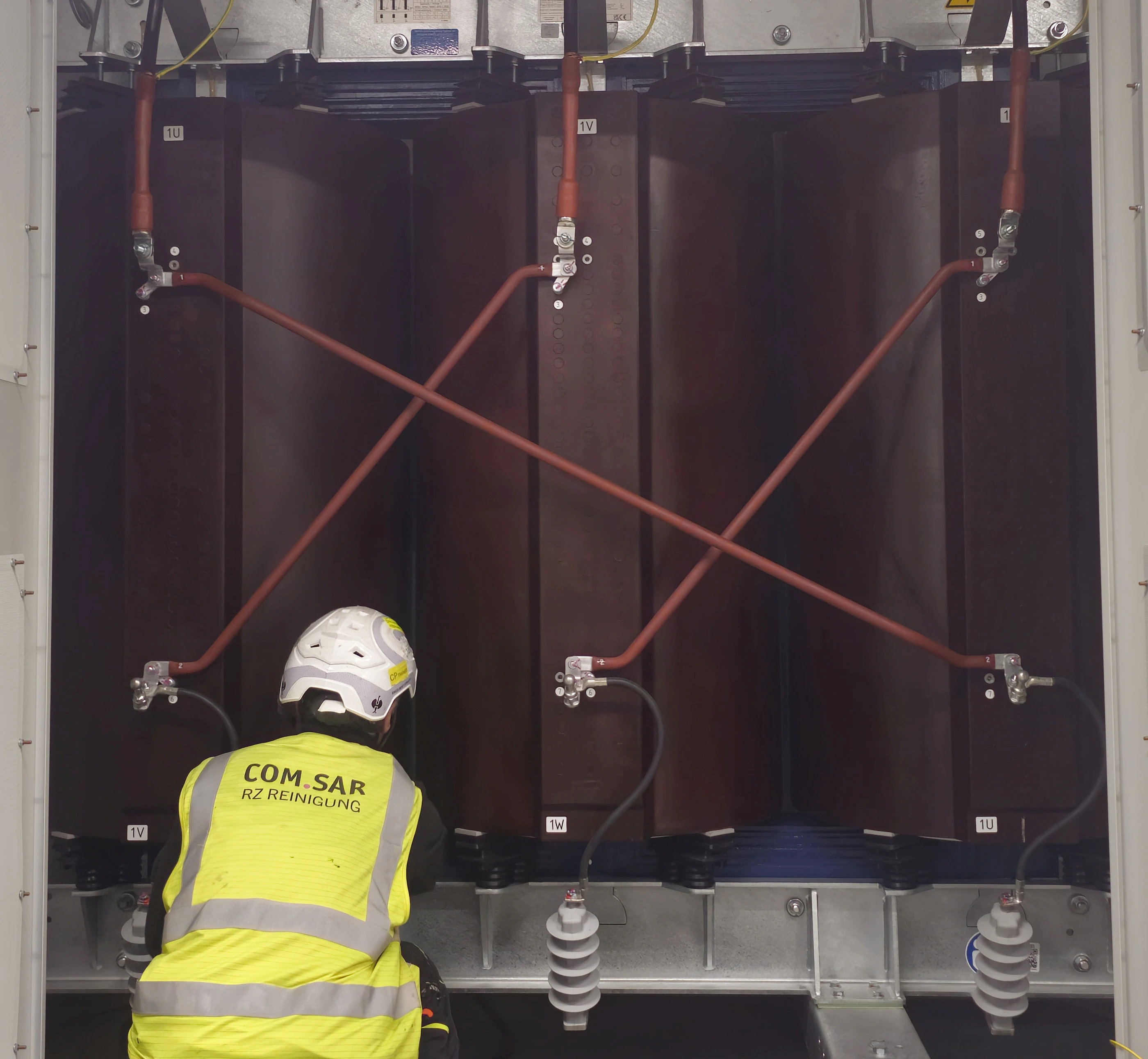 Mitarbeiter von COM.SAR IT Cleaning bei der Reinigung im unteren Bereich eines Transformators.