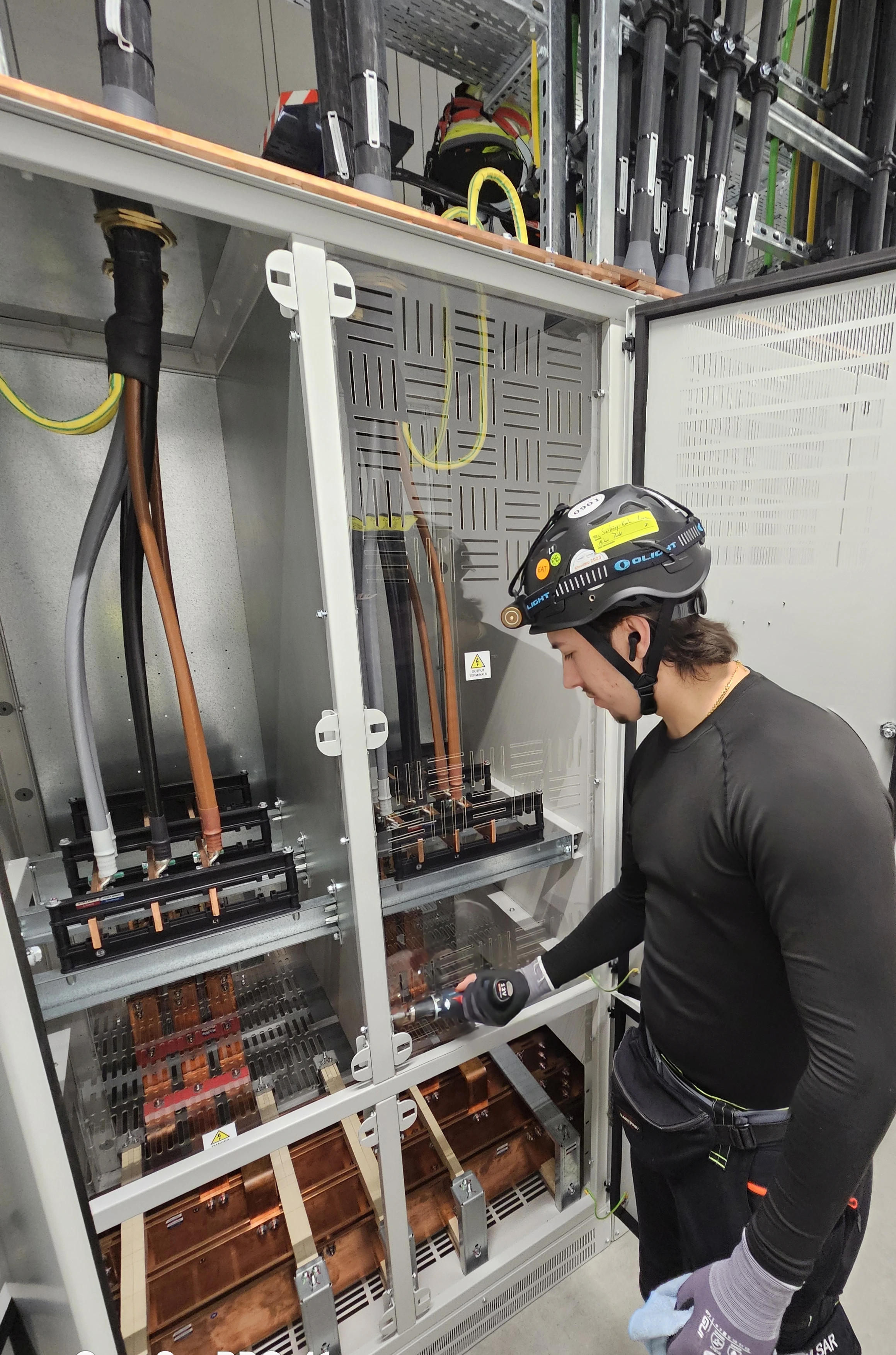 COM.SAR IT Cleaning team member opening a transparent switchgear cover to clean the copper busbars and interior. COM.SAR IT Cleaning team member opening a transparent switchgear cover to clean the copper busbars and interior.