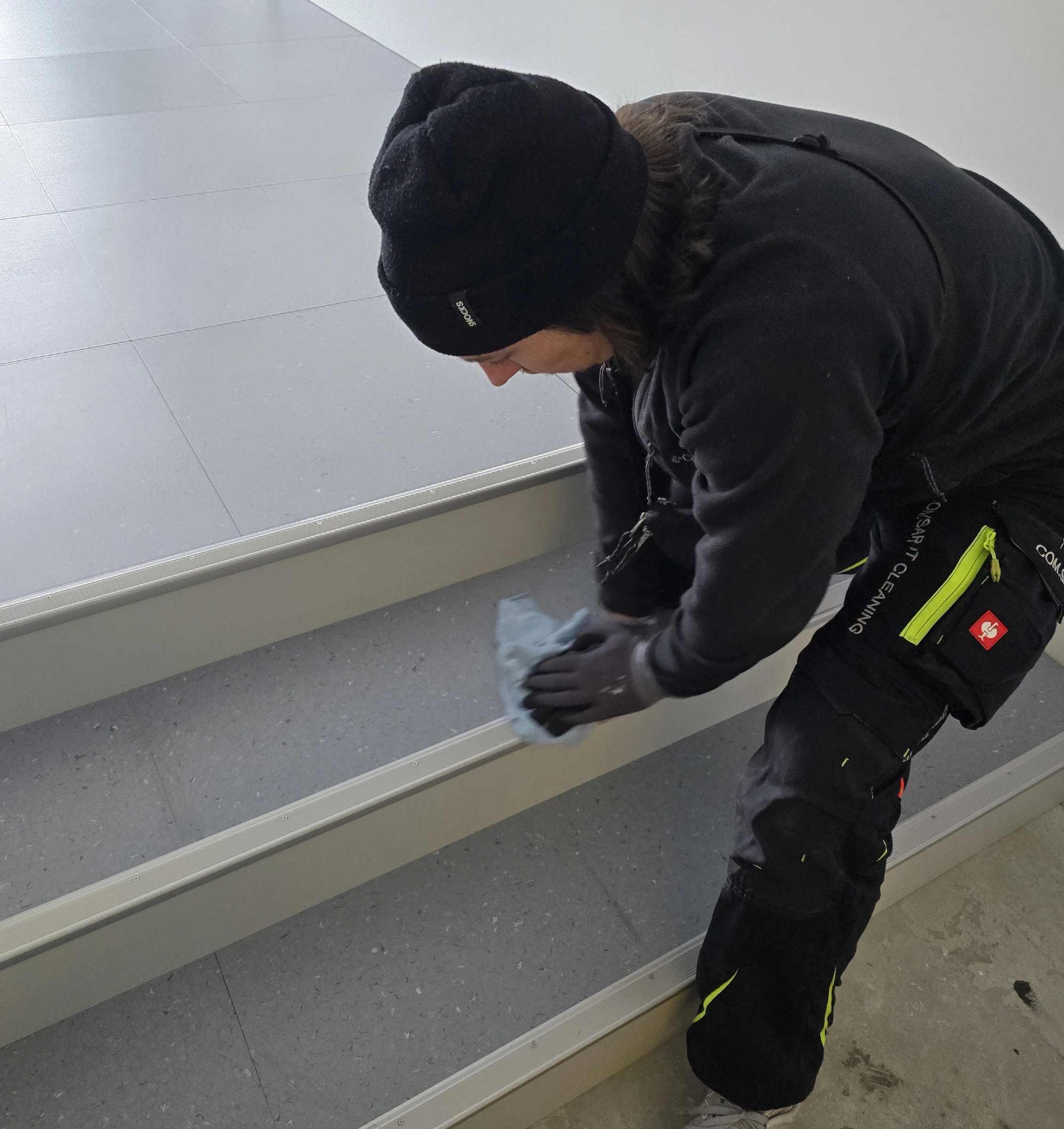 Mitarbeiter reinigt eine Stufe und ihre Trittleiste mit einem Tuch. Mitarbeiter reinigt eine Stufe und ihre Trittleiste mit einem Tuch.